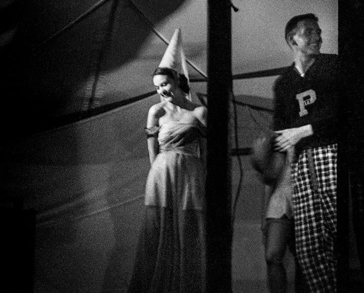 A black and white photo of costumed performers under a tent