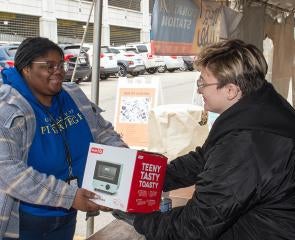 Woman donating toaster during Clutter for a Cause at a table outside