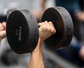 Two hands lift sixty-pound black dumbbells
