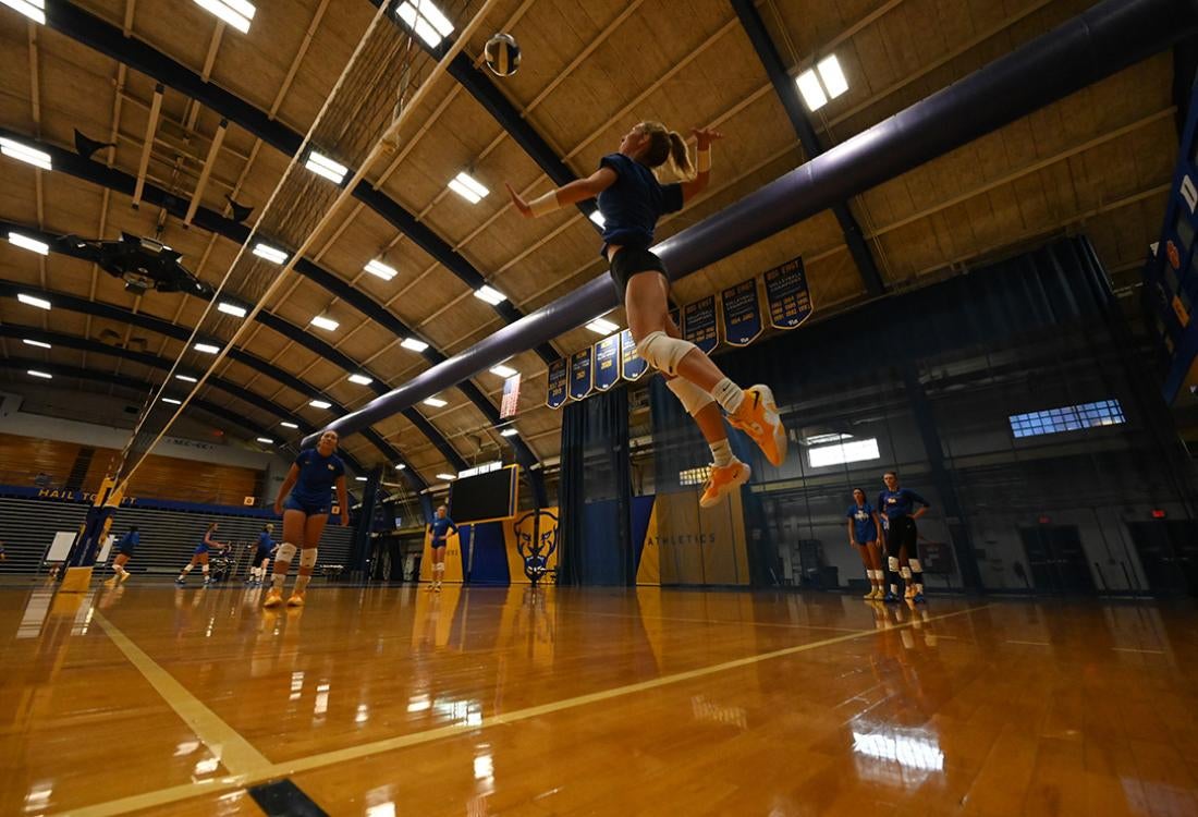 A volleyball player leaps to serve the ball