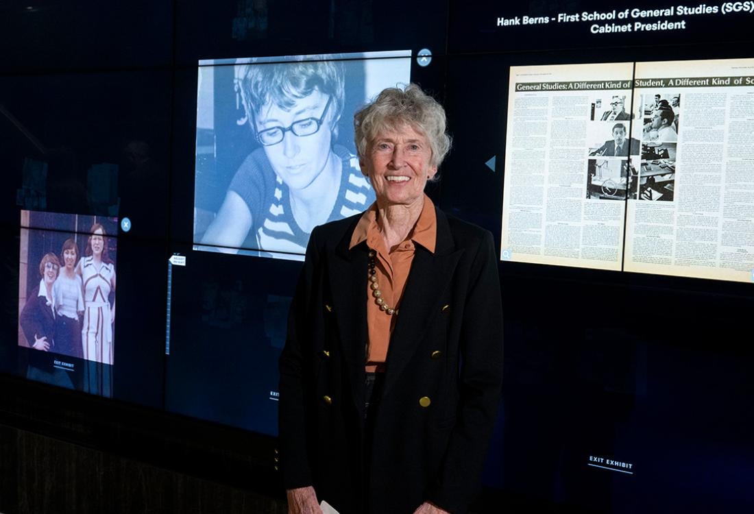 Cushman stands in front of a screen displaying an image of her younger self