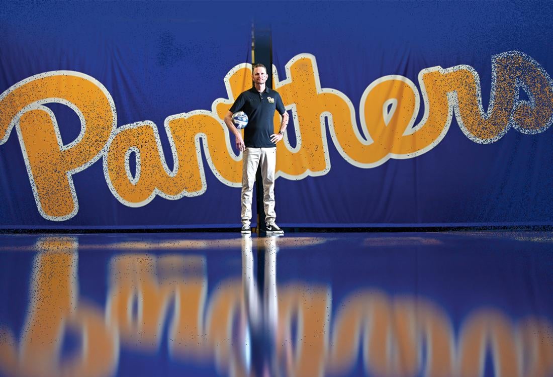 Fisher stands in front of a script Panthers logo