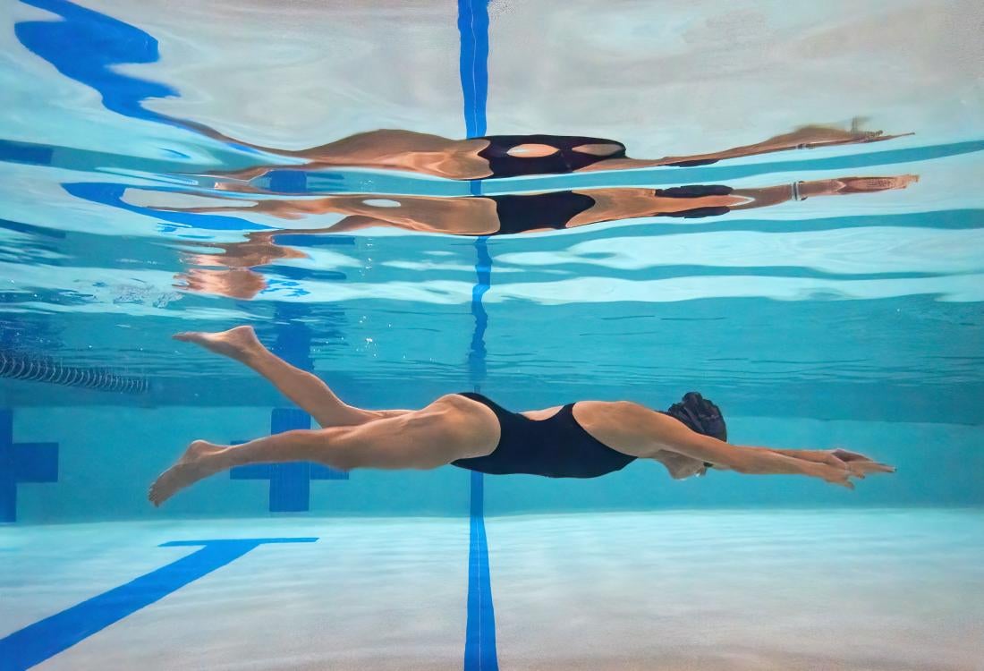 A woman swims underwater in a pool.
