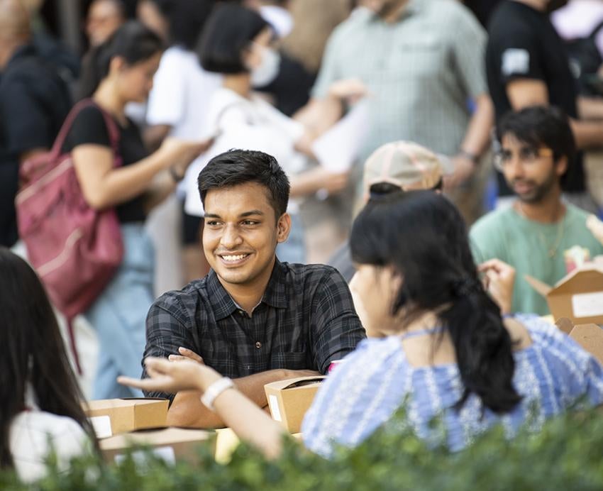 Students sitting at a picnic, smiling 