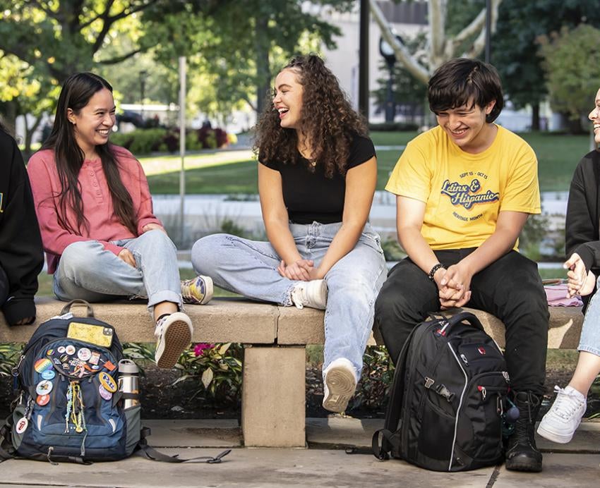 Latinx students sitting together outside with bookbags