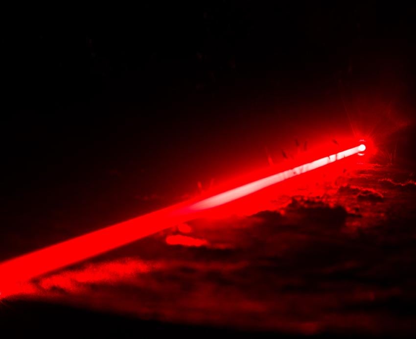 Single red laser beam glowing in dark space