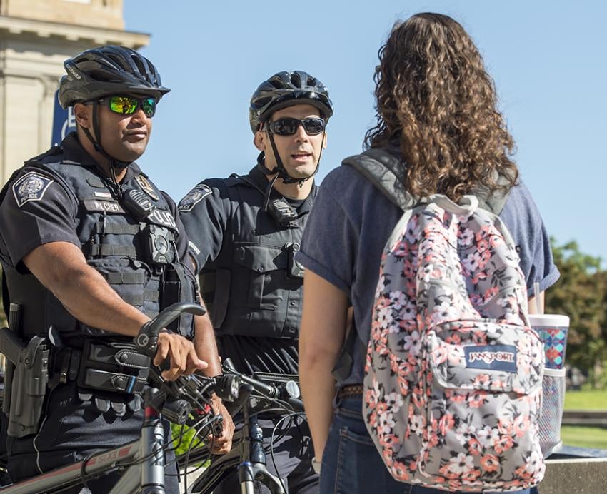 Two police officers talking to students on campus