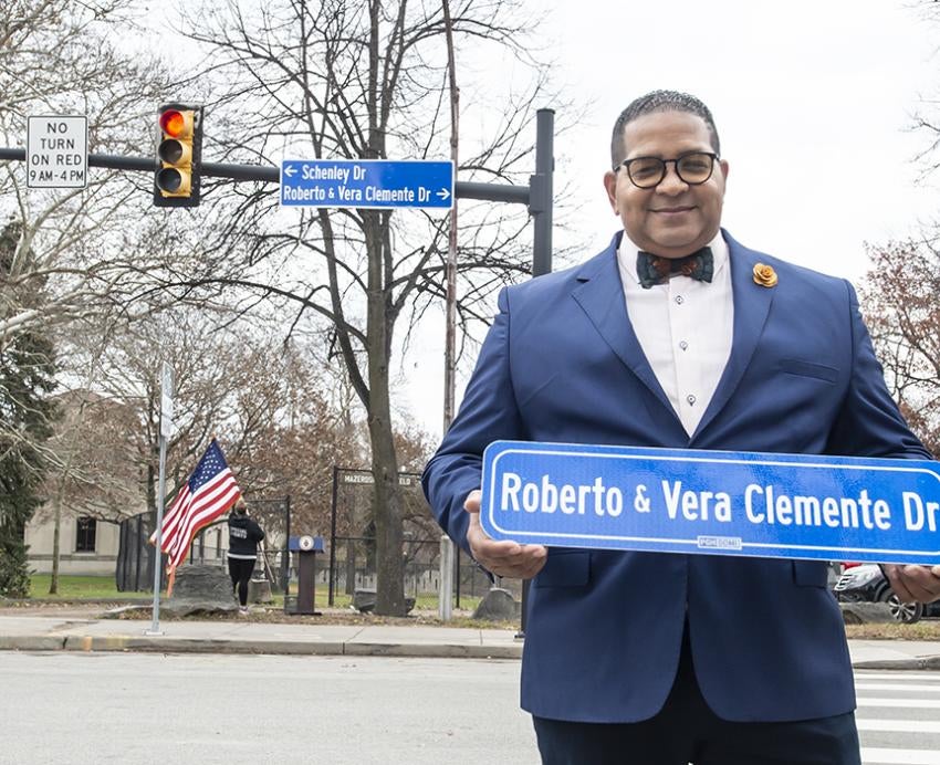 Luis Clemente holding Roberto & Vera Clemente Drive street sign