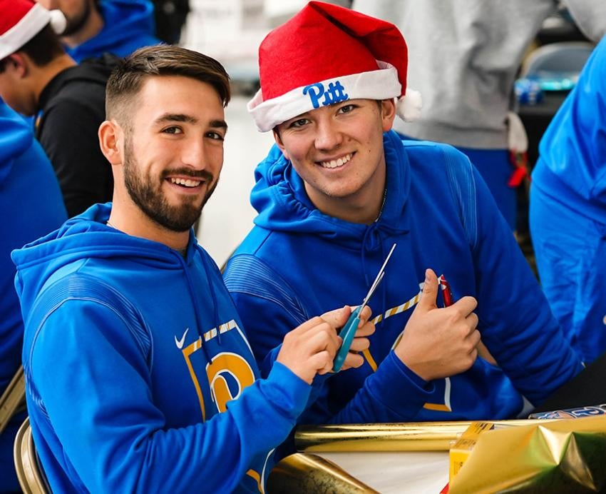 Students wearing Pitt attire and Santa hats with Pitt logo