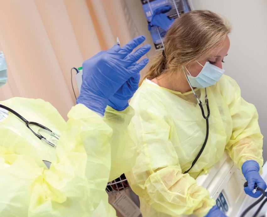 Pitt nurses working together while wearing masks and yellow gowns