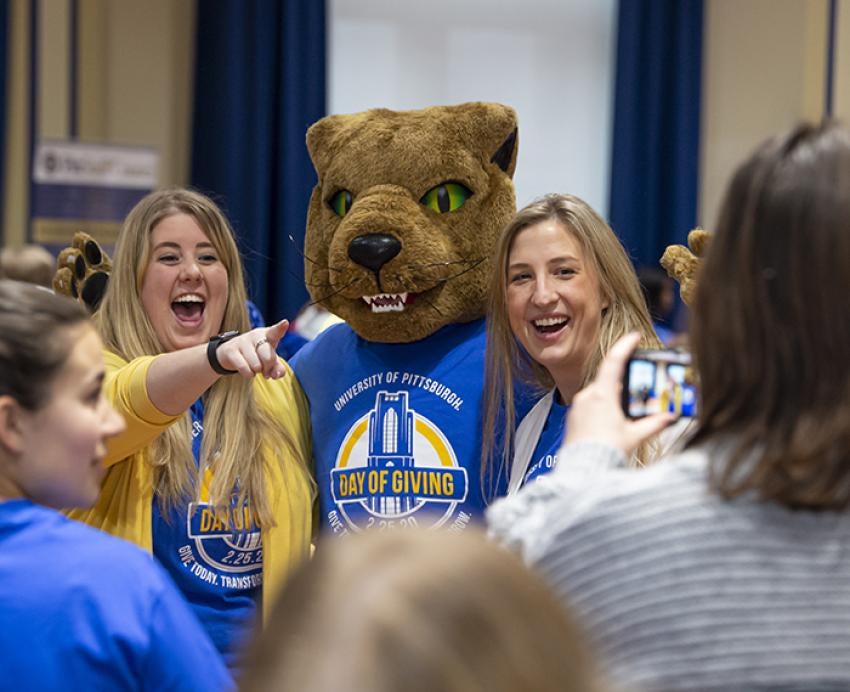 Roc taking a photo with two people during Pitt Day of Giving