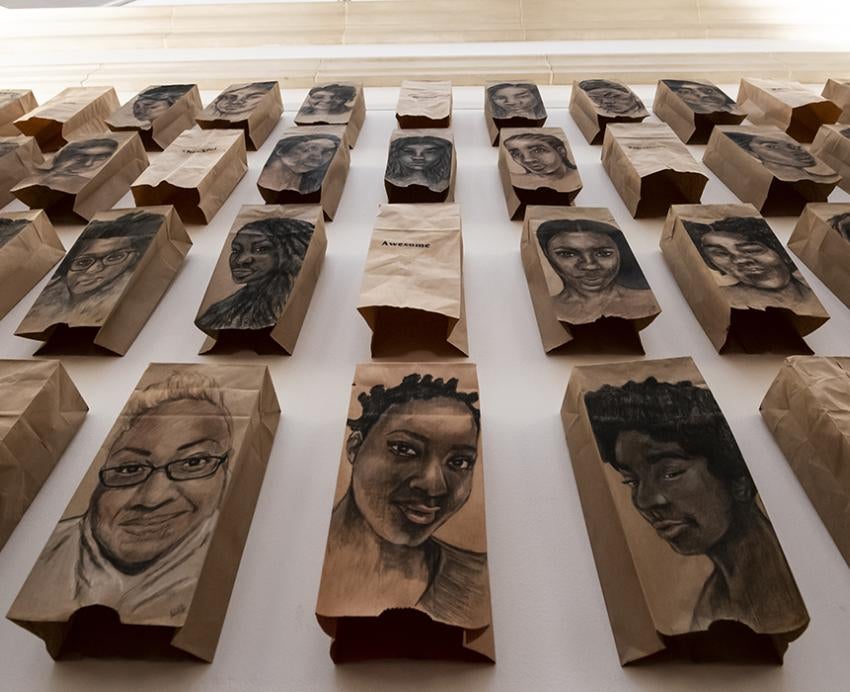 Art exhibition with drawings of people's faces on brown paper bags