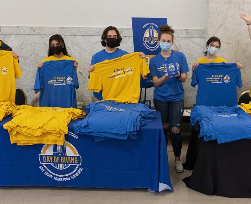 People holding blue and yellow Pitt Day of Giving shirts