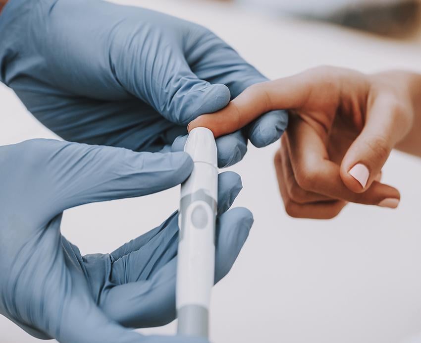 Doctor pricking a patients finger with a needle to test blood sugar