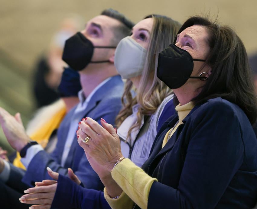 People wearing face masks indoors and clapping their hands