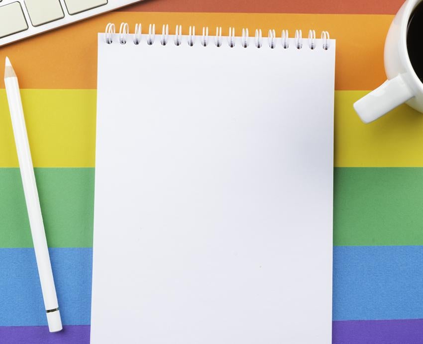 Notebook, pencil, coffee cup and keyboard on a rainbow background