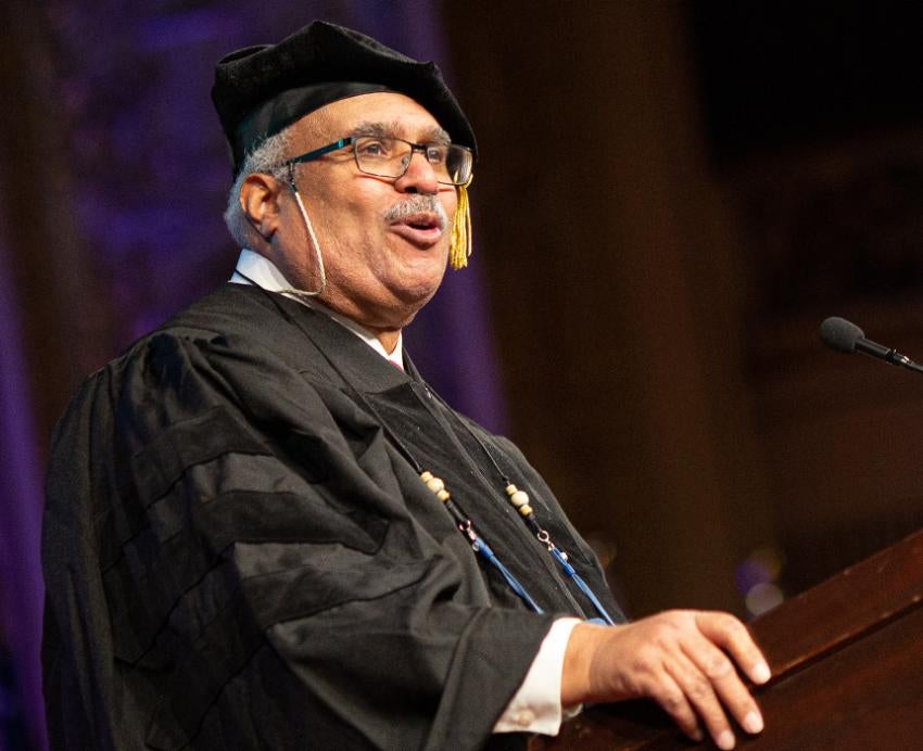 Georges Benjamin in cap and gown speaking at the commencement ceremony