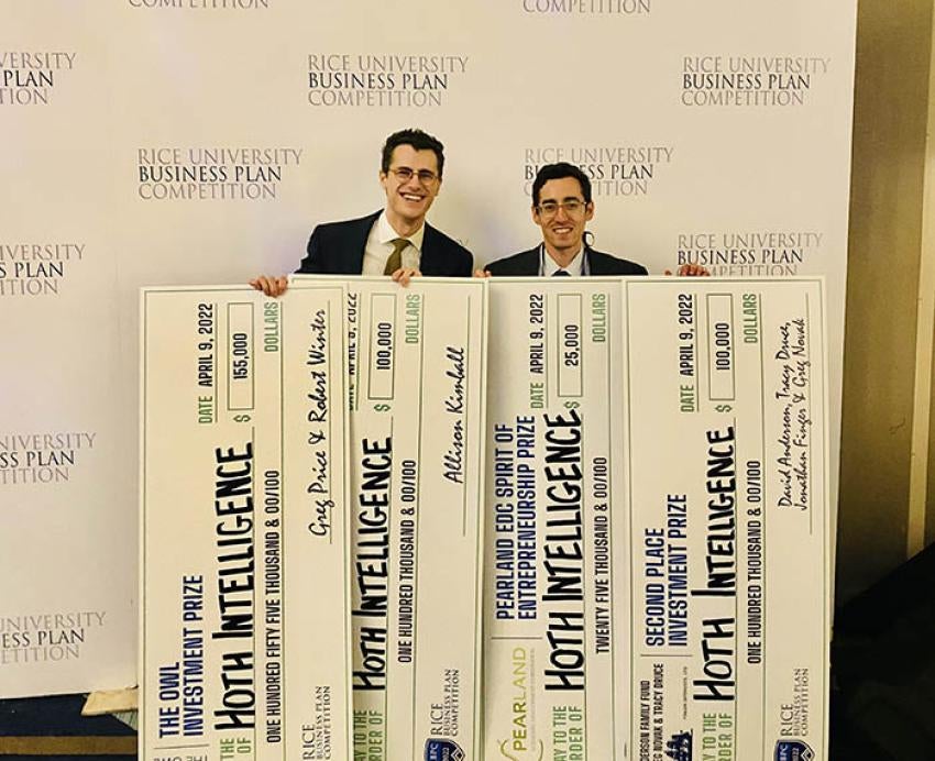 Two men holding four large checks together