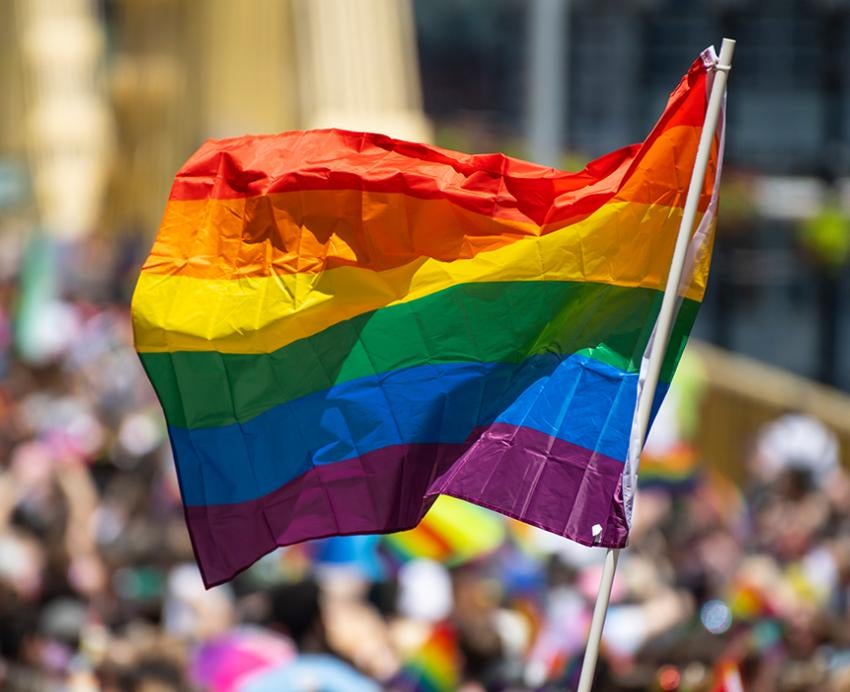 a rainbow flag held above a crowd