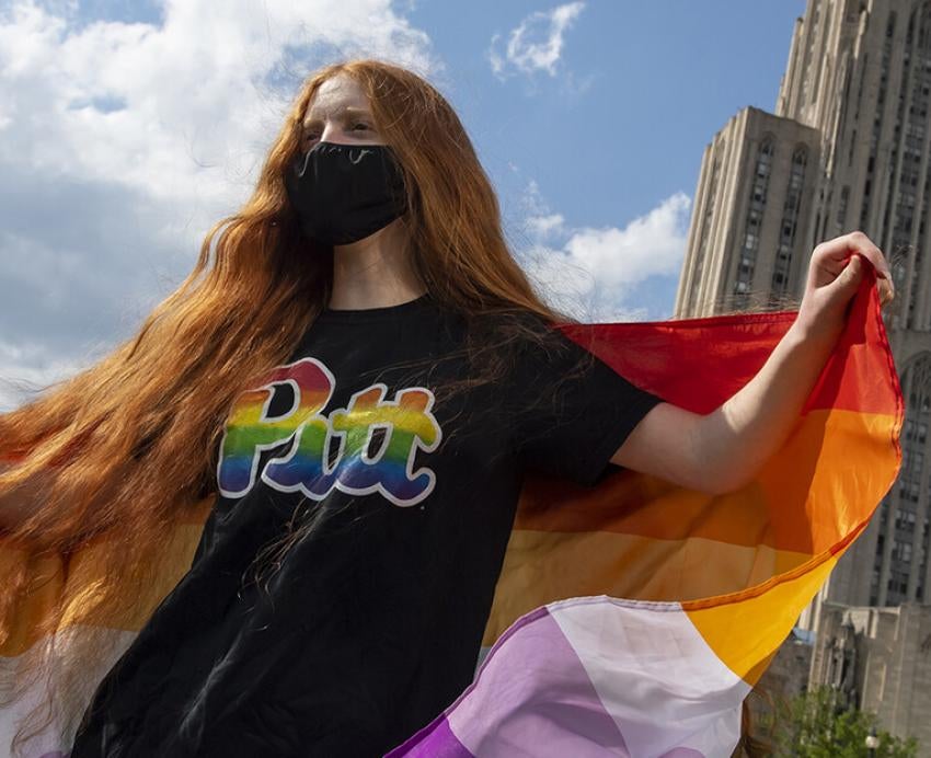 a woman carries a pride flag in front of the cathedral 