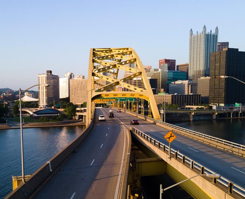 the long road and arch of a yellow bridge in Pittsburgh