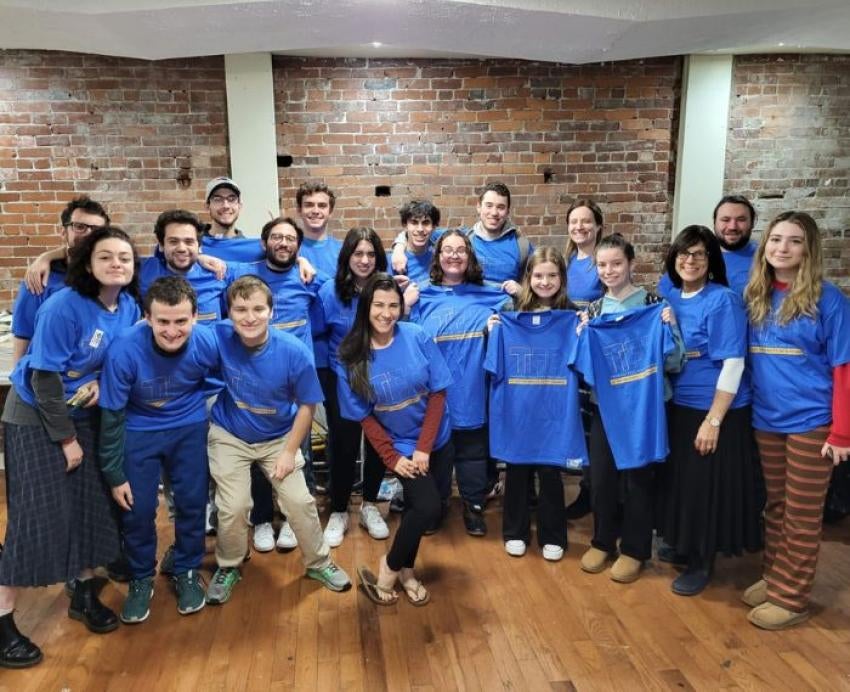 A group wearing matching blue shirts that read Twerski Fellows Program smile.