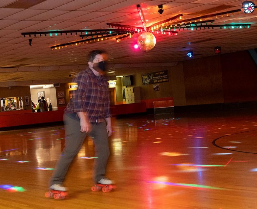 a person at a skating rink with festive lights shining down
