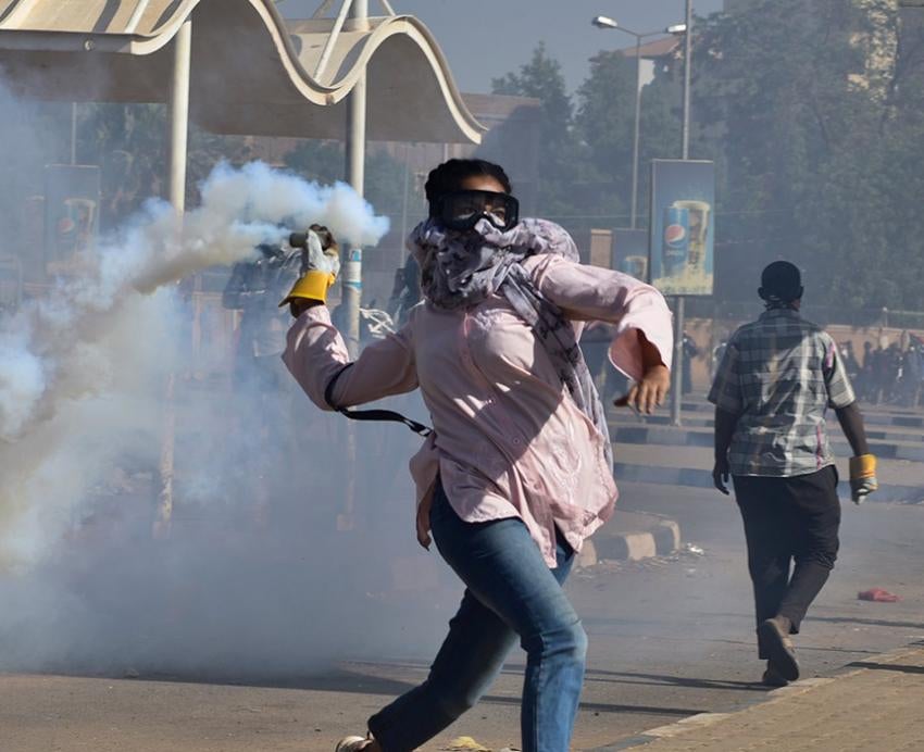 a protestor throwing a smoking object