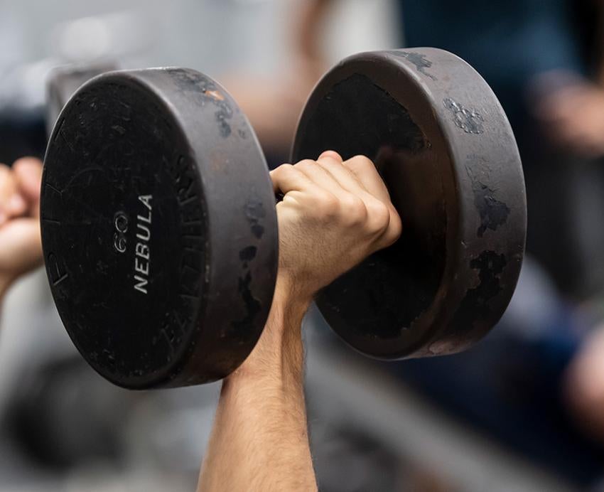 Two hands lift sixty-pound black dumbbells