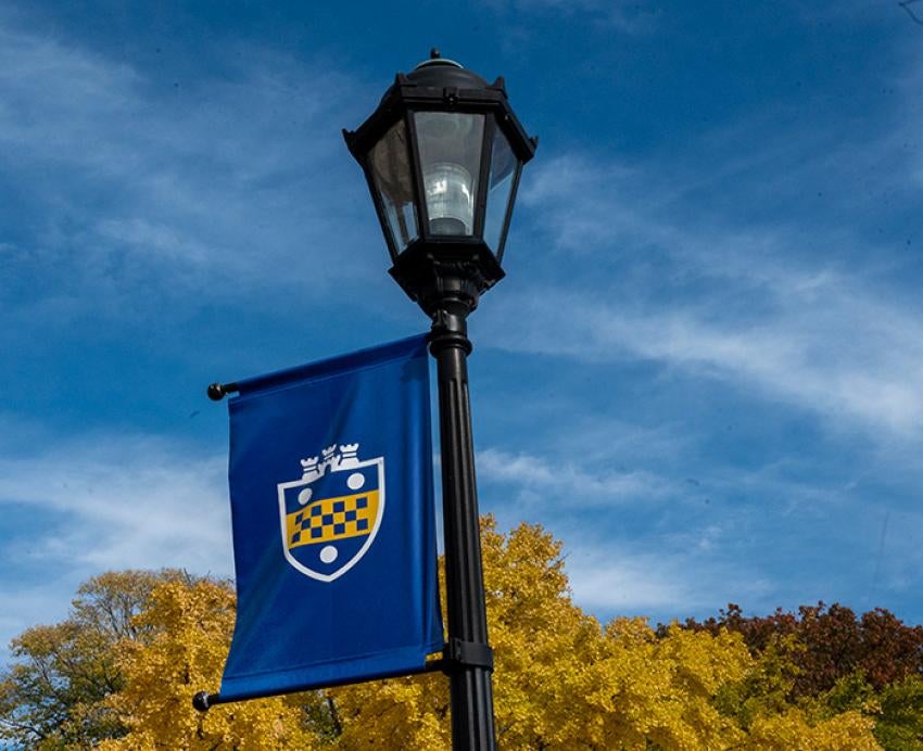 The Pitt shield on a blue flag hanging from a lamppost