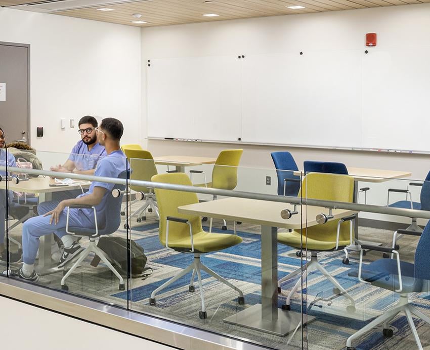 Students in scrubs sit in a lofted study area in Salk Hall
