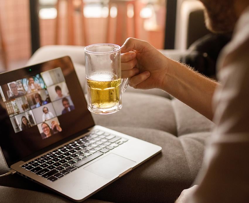 A glass of beer held up in front of a video call meeting