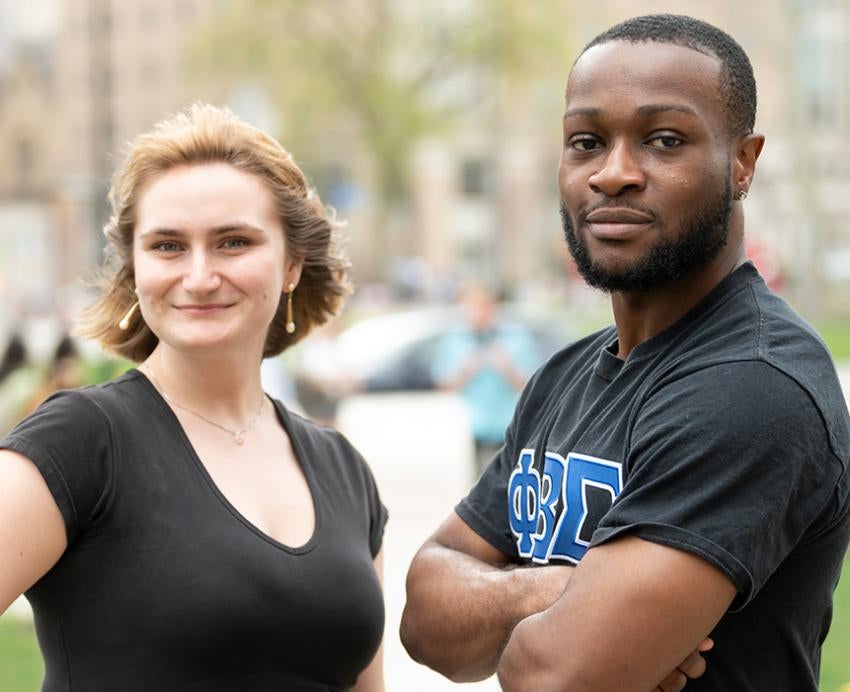 A two people in black shirts pose for a portrait outdoors