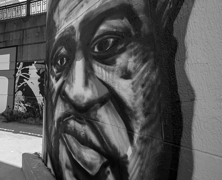 A black-and-white photo of a painting of George Floyd's face on a bridge underpass in Downtown Pittsburgh