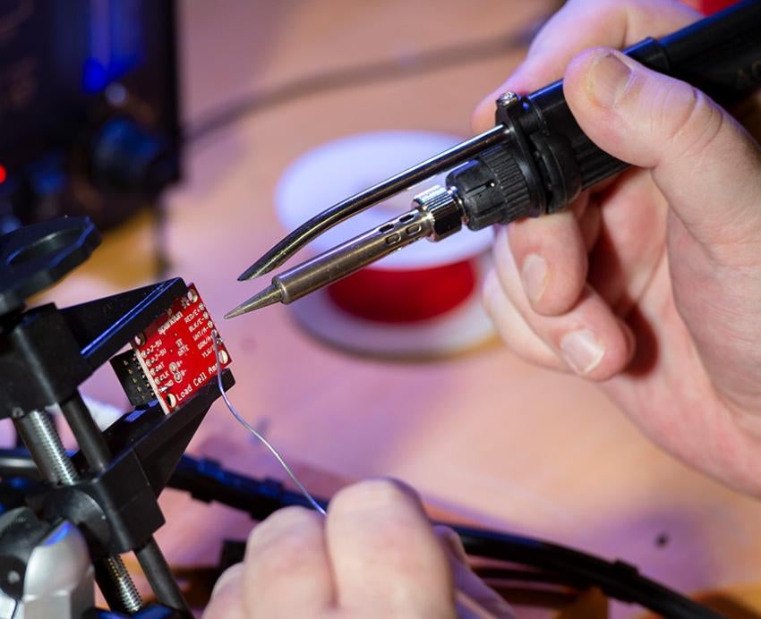 Hands soldering a piece of electronic equipment