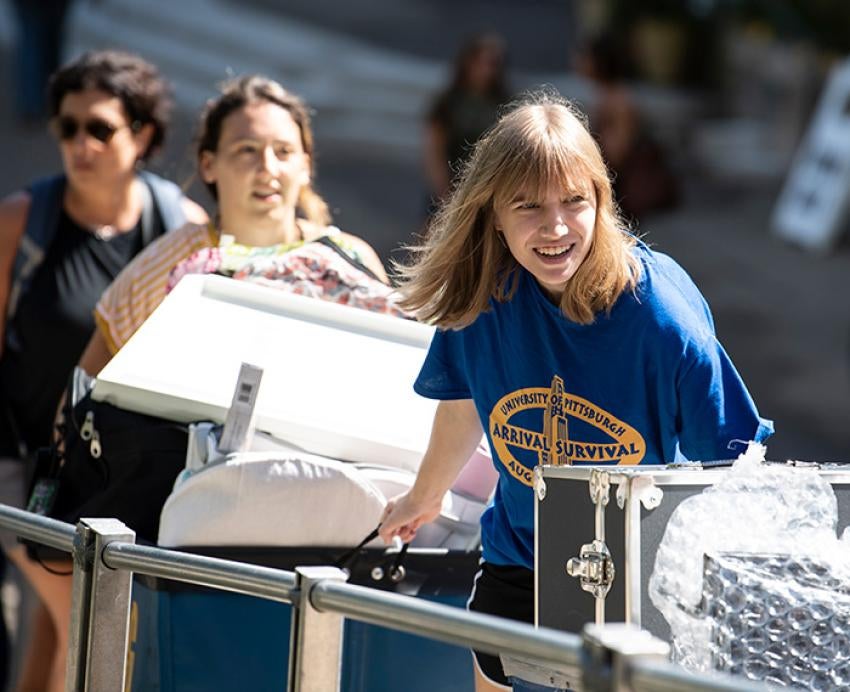 A volunteer in a blue shift pushes moving carts