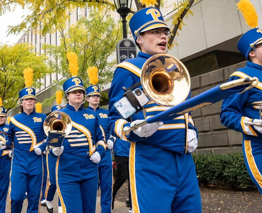 A band in blue and gold uniforms marches in two single file lines