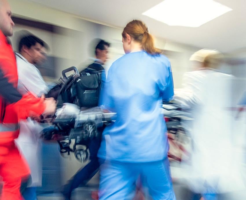 Doctors, nurses and EMS workers rush a stretcher through a hospital