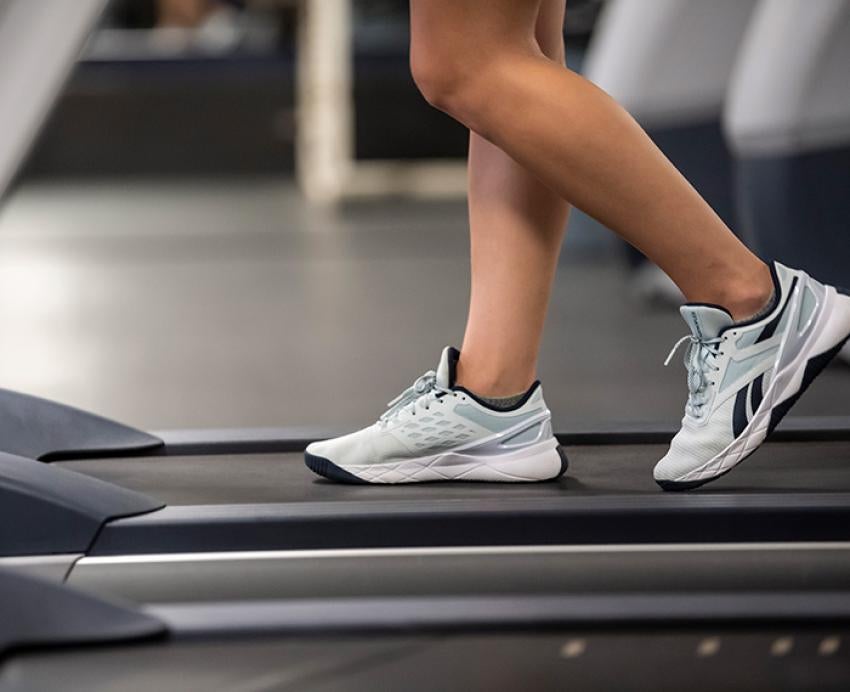 Two legs wearing athletic shoes walk on a treadmill