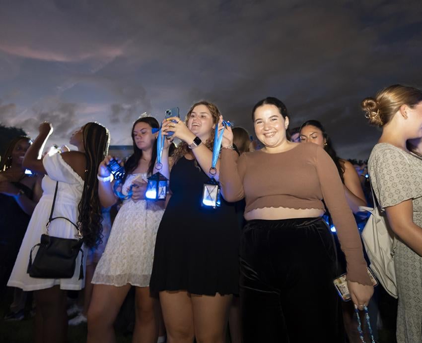 a line of people holding lanterns, taking photos and smiling