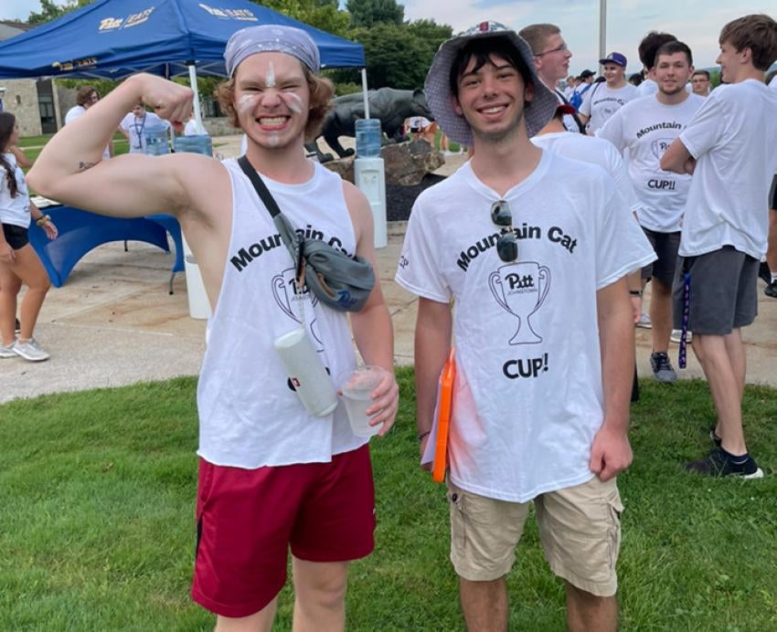 Two students pose in white Mountain Cat Cup T-shirts