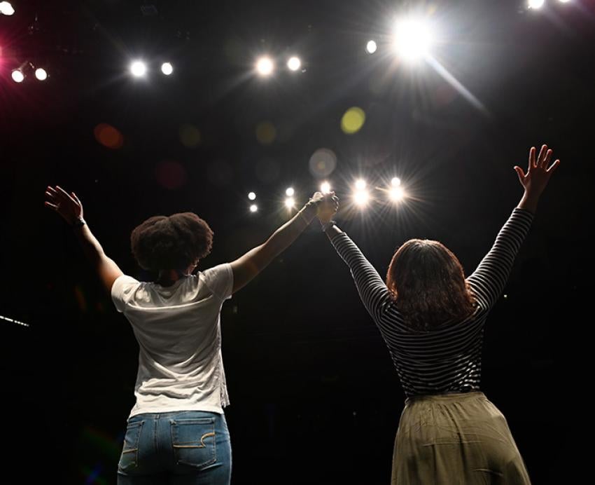 Two people hold their hands up on stage