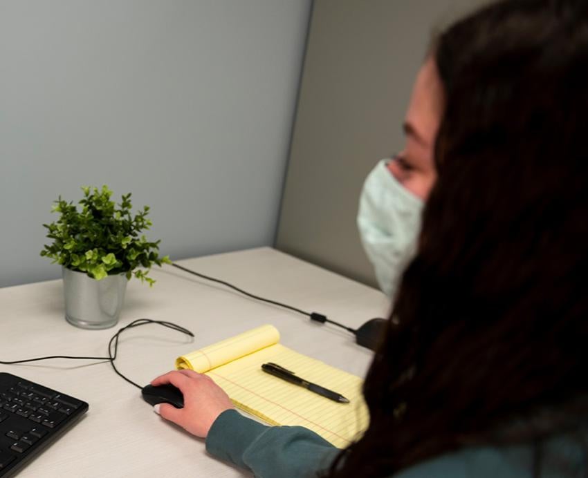 A person wearing a face mask talks to a therapist on a video call