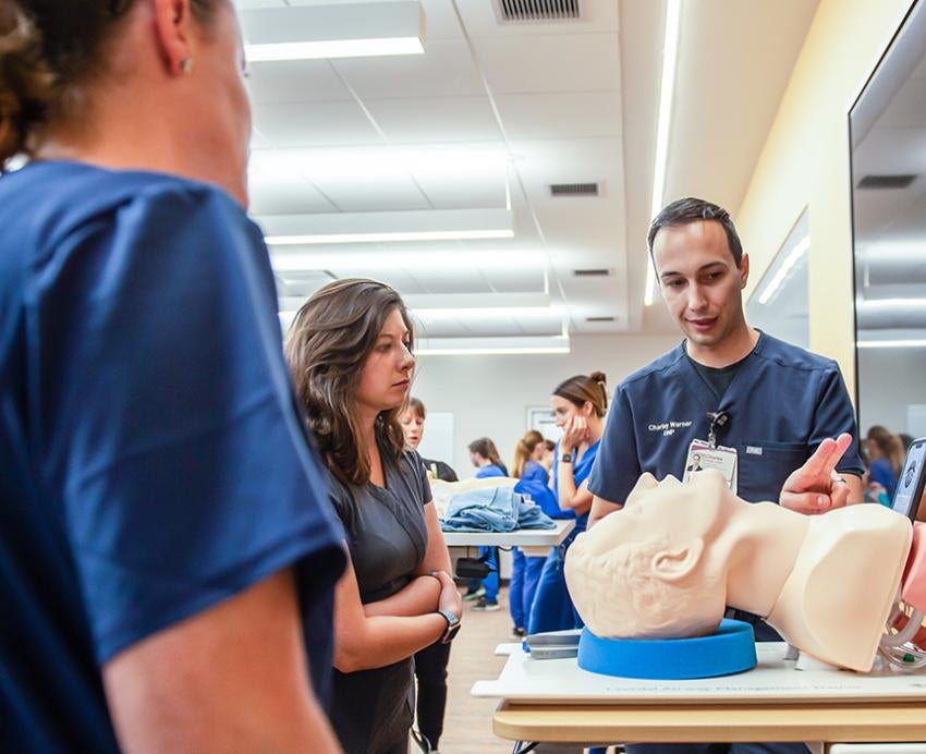 several nursing students surrounding a dummy patient head