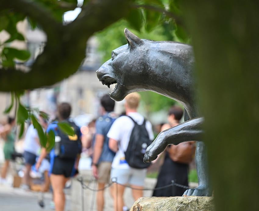 People walk past a panther statue on Pitt's campus