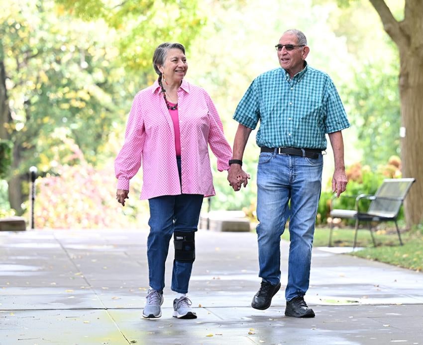 An older couple walks hand-in-hand on Pitt's campus