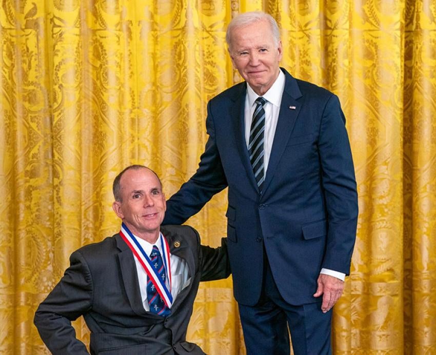 Cooper, wearing a medal, poses with President Biden