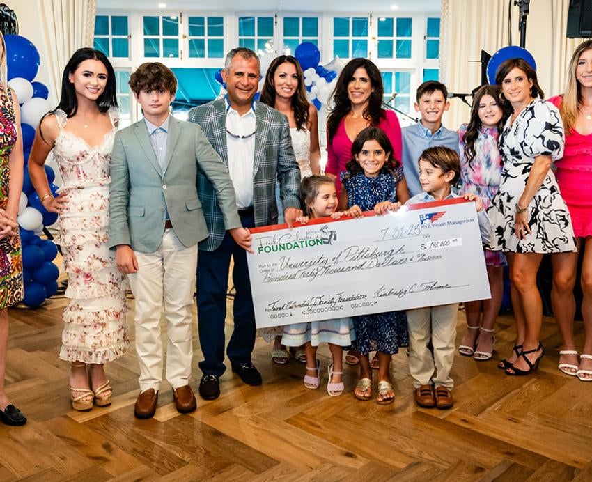 A group of people in formal wear hold a giant check