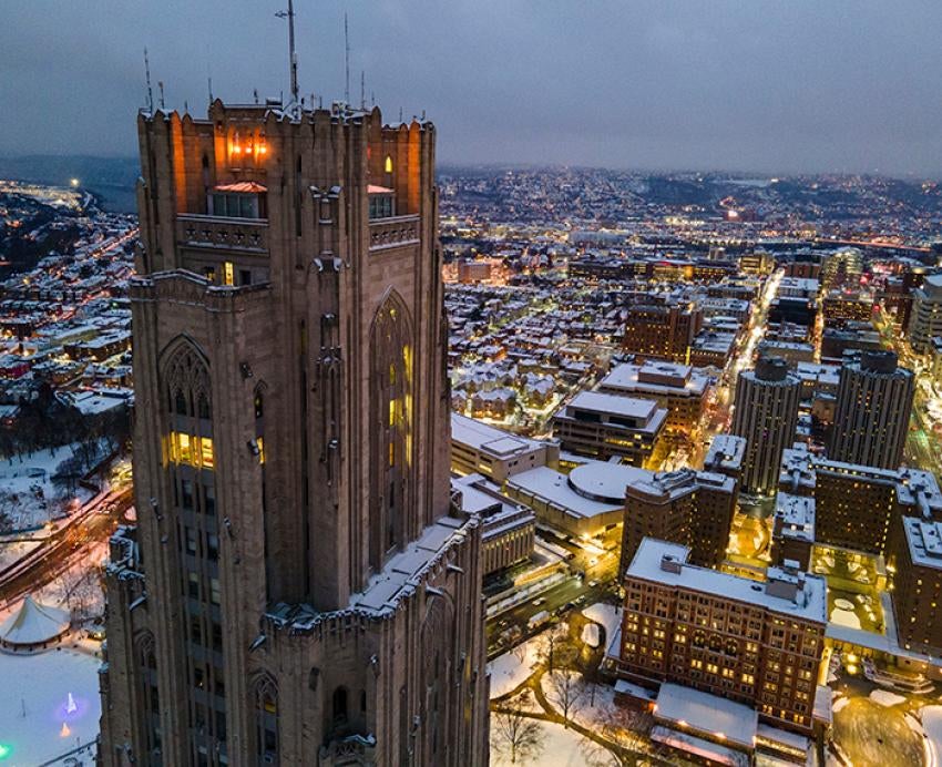 A drone photo of the Cathedral of Learning and Pitt's campus on a snowy day