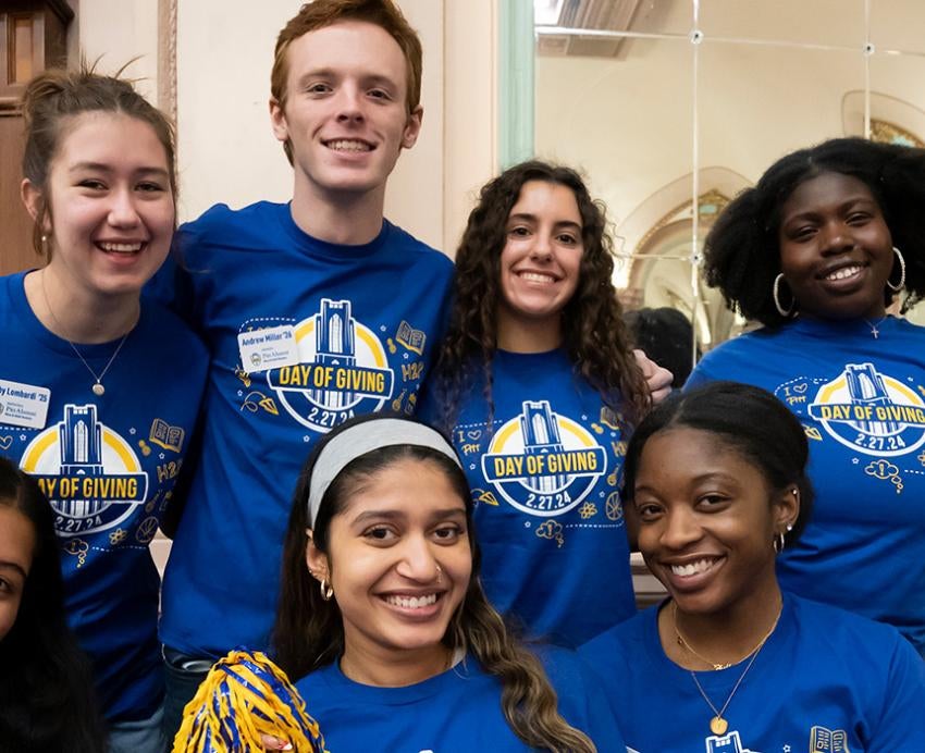 A group of students in blue Pitt Day of Giving shirts smile